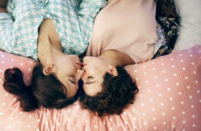 Dve ženy ležia vedľa seba v posteli a bozkávajú sa.jpg